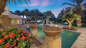 A pool area with stone planters and palm trees. - PalmSpring Luxury Vacation Home-Salted Pool & Spa. (Thousand Palms)