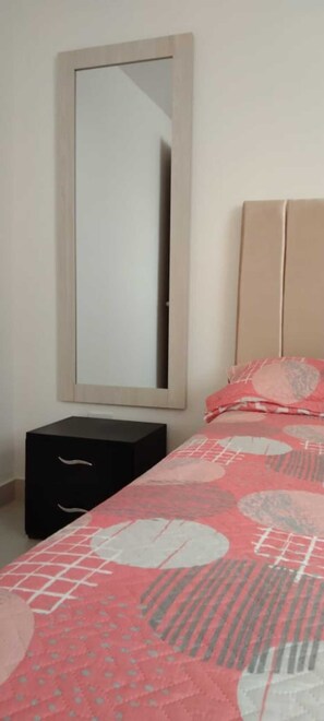 Relax in a stylish bedroom with a large mirror and a comfortable bed dressed in a patterned bedspread.