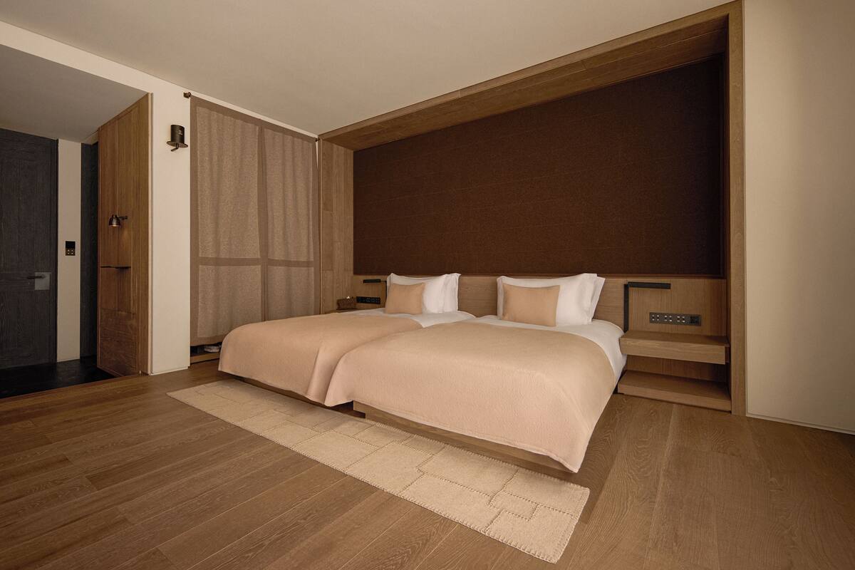 Une chambre moderne avec un grand lit, une tête de lit en bois et une étagère intégrée.