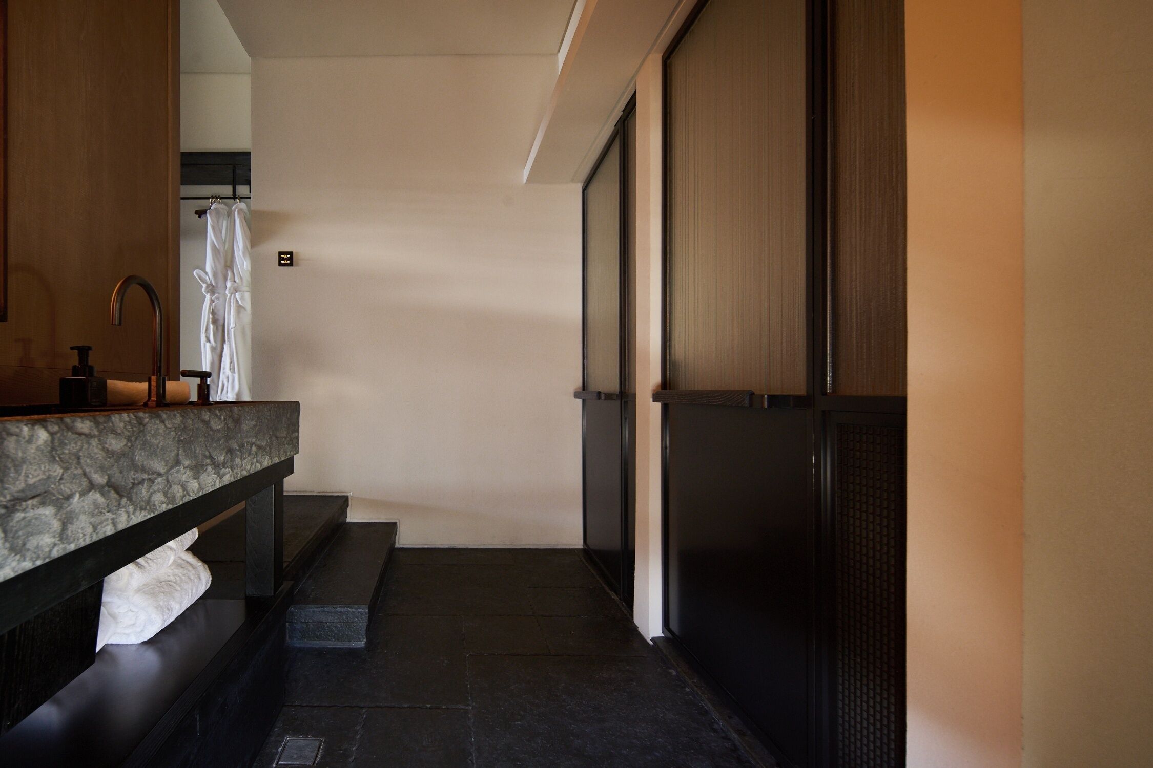 A modern bathroom with a marble countertop, a black sink, and a glass shower enclosure.