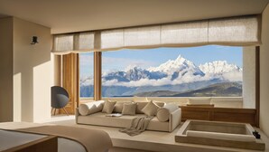 Un dormitorio moderno con un ventanal grande, un sofá, una cama y una mesita.