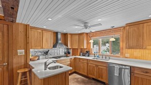 Une cuisine moderne avec des meubles en bois, un îlot central doté d’un évier, d’une cuisinière et d’un lave-vaisselle.