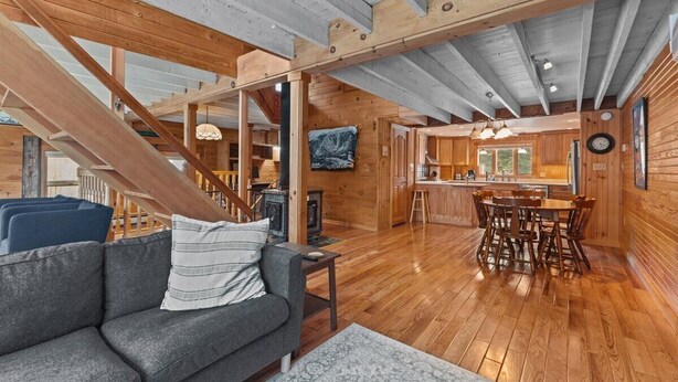 Un vaste espace de vie agrémenté d’un escalier en bois, d’une cheminée et d’un coin repas avec des meubles en bois.