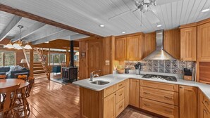 Une cuisine spacieuse avec des meubles de rangement en bois, un grand îlot central doté d’un évier et une cuisinière.