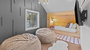 Une pièce confortable avec un lit, une télévision et une fenêtre donnant sur les arbres.