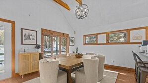 Un coin repas avec une table en bois, six chaises et un lustre.