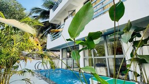 Ein modernes Gebäude mit Swimmingpool, umgeben von tropischer Vegetation.