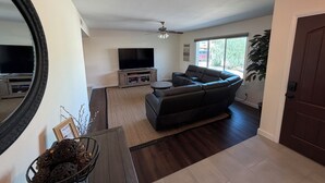 Ein Wohnzimmer mit einer Couch, einem Fernseher und einem Deckenventilator.