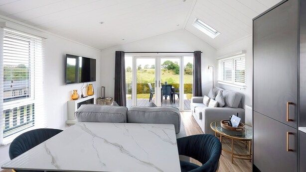 A modern interior with a dining area, sofa, and a TV mounted on the wall. - 2 bedroom accommodation in Old Langho, Ribble Valley (Old Langho, Ribble Valley)