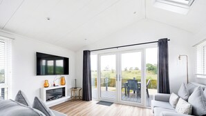 A modern living room with a flat-screen TV, fireplace, and a sliding glass door leading to an outdoor patio. - 2 bedroom accommodation in Old Langho, Ribble Valley (Old Langho, Ribble Valley)