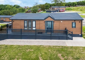 A modern building with a wooden facade, a black roof, and a covered porch with a black railing. - 1 bedroom accommodation in Old Langho, Ribble Valley (Old Langho, Ribble Valley)