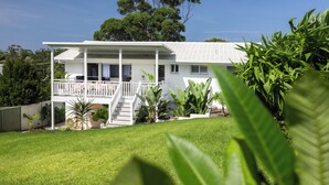 A two-story house with a balcony, surrounded by greenery and trees. - Palm Springs by the Beach, Glam, Pet-Friendly, 4 Bed Retreat incl HUGE studio. (Mollymook Beach)