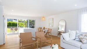 A modern living room with a sofa, chairs, a dining table, and a balcony with outdoor furniture. - Palm Springs by the Beach, Glam, Pet-Friendly, 4 Bed Retreat incl HUGE studio. (Mollymook Beach)