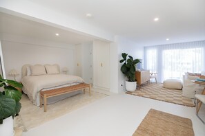 Une chambre moderne avec un lit, un banc, des plantes en pot et un tapis à carreaux.