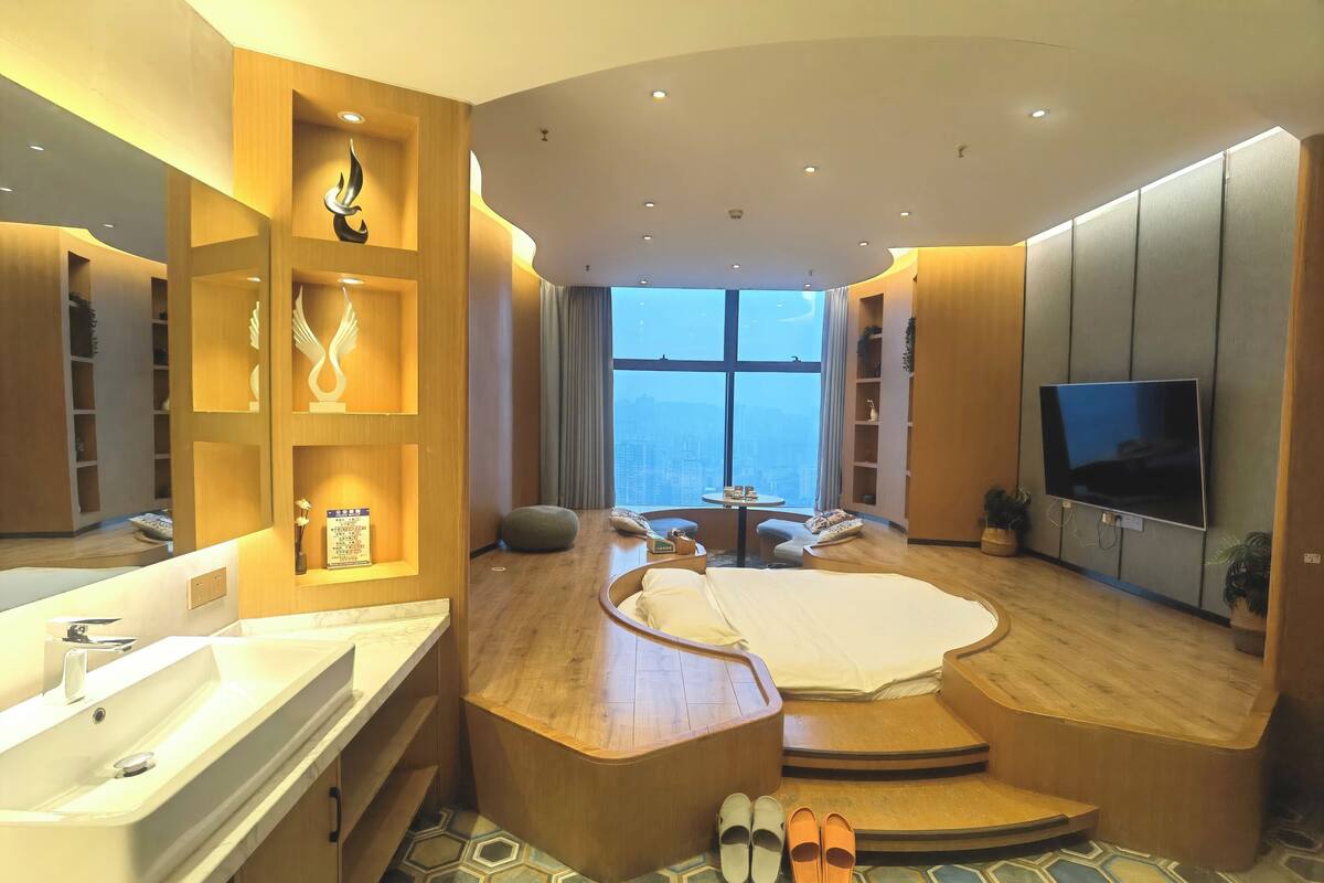 Une chambre d’hôtel moderne dotée d’un grand lit, d’une télévision, d’une salle de bain avec lavabo et offrant une vue sur la ville.