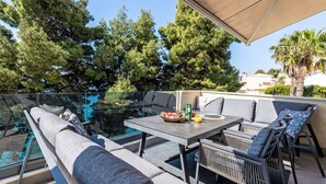 A rooftop terrace with a glass balustrade, outdoor seating, and a view of the sea and trees. - Apartment Tina by Interhome (Trogir/Okrug Gornji)