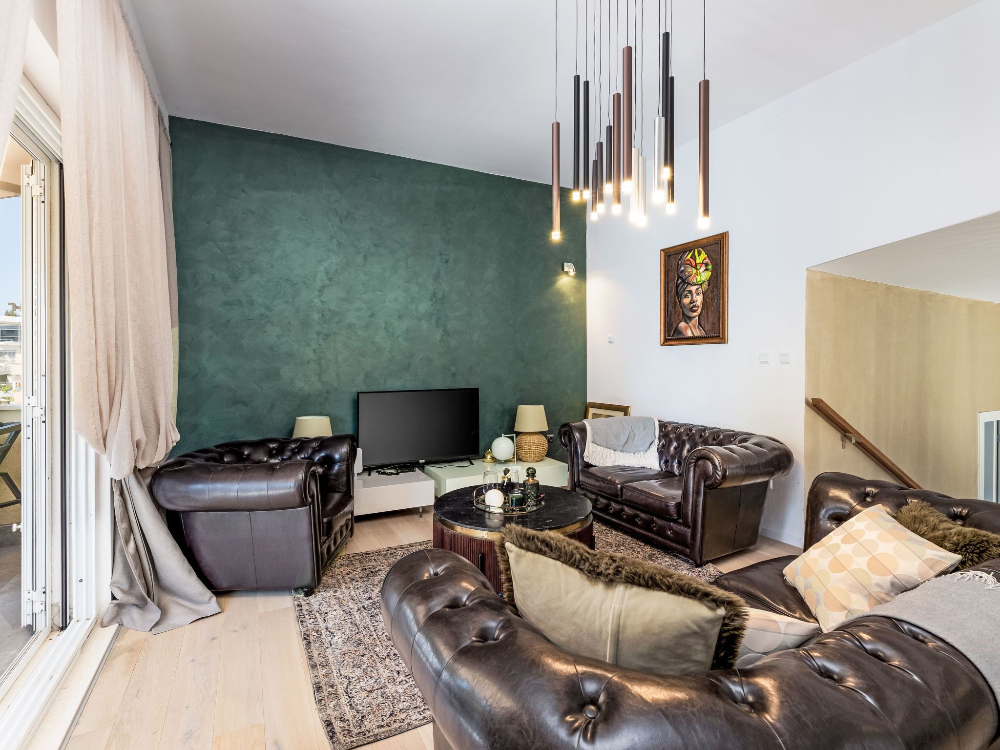 Un salon moderne avec des canapés en cuir, un téléviseur à écran plat et un mur d’accent vert.