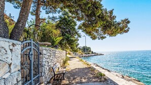 A coastal walkway with a stone wall, a bench, and a view of the sea. - Apartment Tina by Interhome (Trogir/Okrug Gornji)