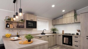 Une cuisine moderne avec des meubles en bois, un îlot central, un four à micro-ondes et une cuisinière à gaz.