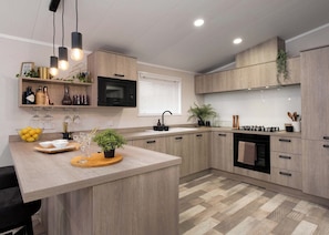 Une cuisine moderne avec des meubles en bois, un îlot central, un four à micro-ondes et une cuisinière à gaz.
