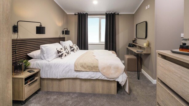 Une chambre à coucher moderne, avec un lit, des tables de chevet, un bureau, un miroir et une fenêtre.