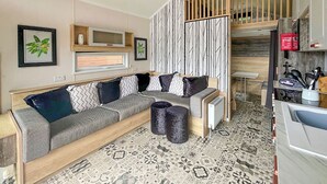 A modern living room with a sofa, a coffee table, and a kitchen area with a sink and stove. - 2 bedroom accommodation in Gartmore (Gartmore)