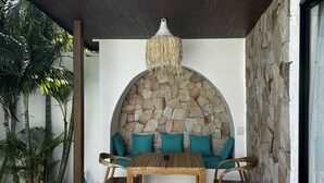 A covered outdoor seating area with a stone wall, wooden furniture, and a hanging light fixture. - Villa With Private Pool Near Fisherman`s (Bo Phut)