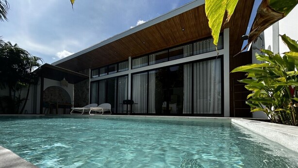 A modern pool area with clear water, a wooden deck, and a large windowed room in the background. - Villa With Private Pool Near Fisherman`s (Bo Phut)