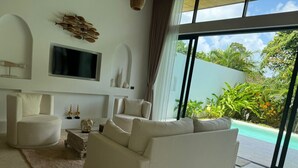 A modern living room with a large window, a flat-screen TV, and a pool view. - Villa With Private Pool Near Fisherman`s (Bo Phut)
