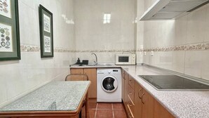 Een kleine keuken met een wasmachine, een magnetron en een spoelbak.
