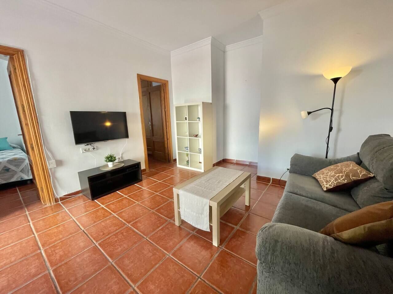 Un soggiorno con un divano, un tavolino, una TV e un mobile.