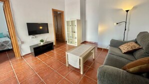 Een woonkamer met een bank, een salontafel, een televisie en een kast.