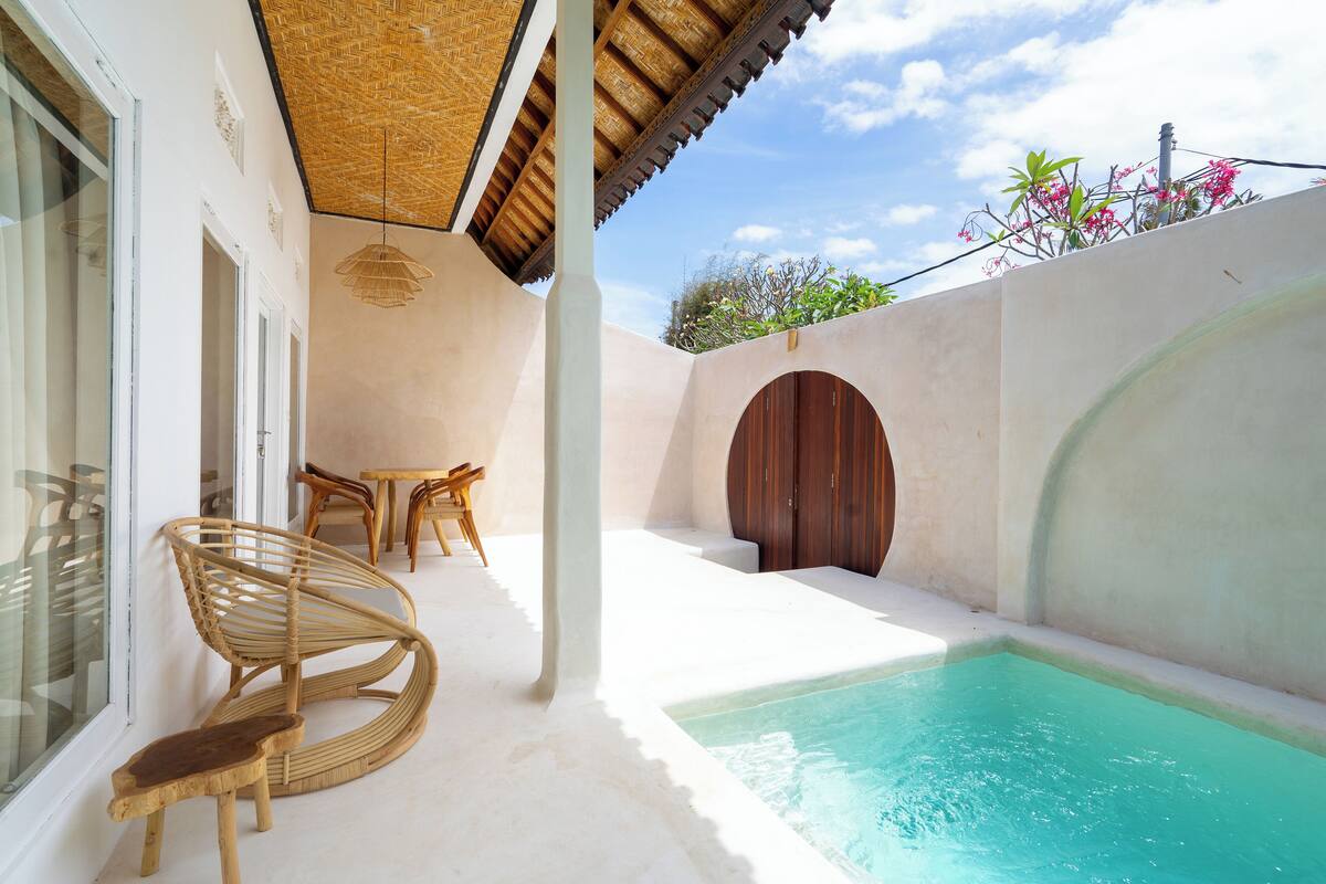 Zona de piscina con puerta de madera, una silla y una mesa.
