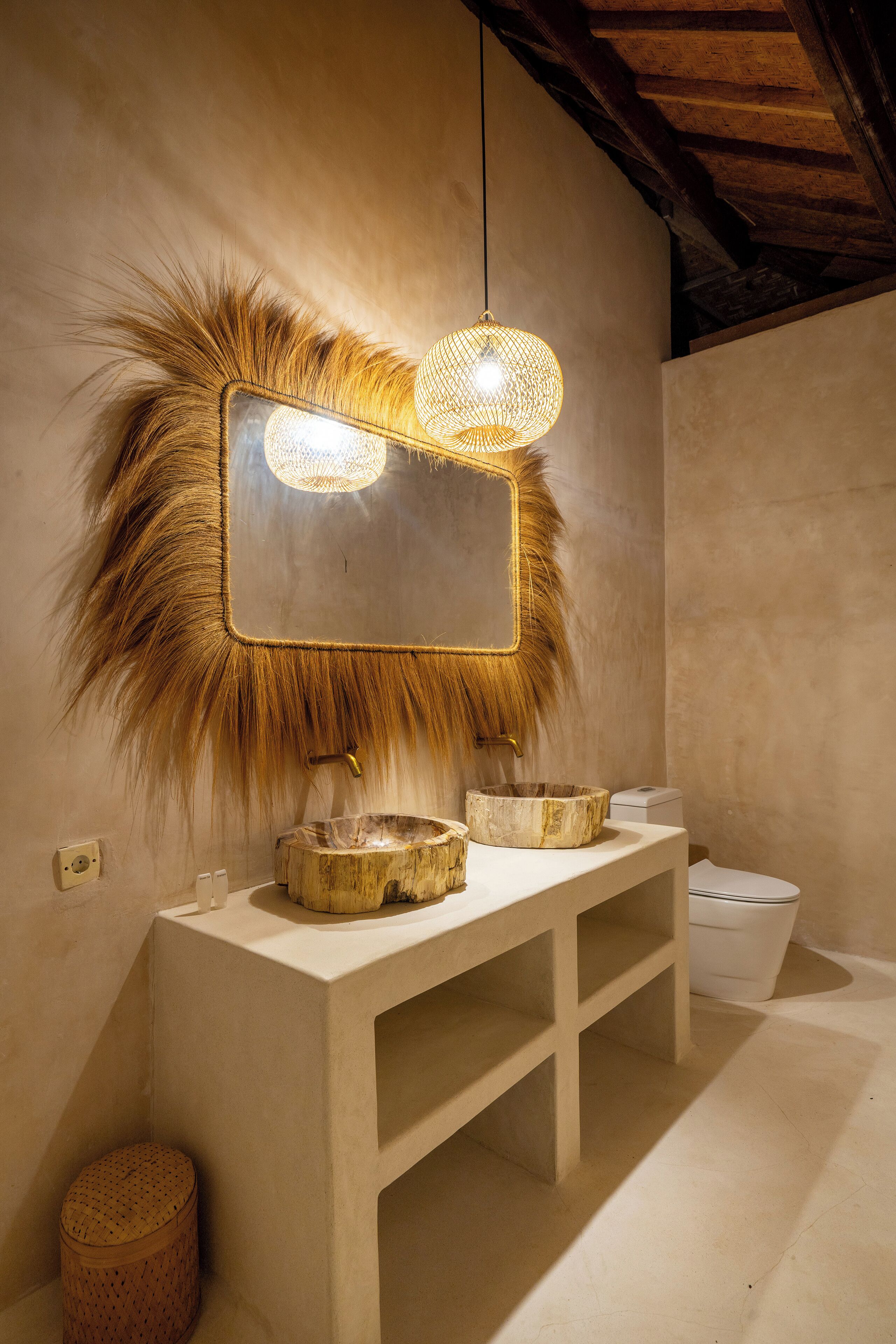 A bathroom with a wooden vanity, a large mirror with a textured frame, and a hanging light fixture.