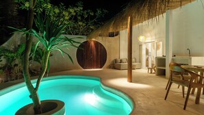 A pool area with a curved edge, a wooden planter with a tree, a thatched roof structure, and a dining area with chairs and a table. - Wellhouse Villas (Lembongan Island)