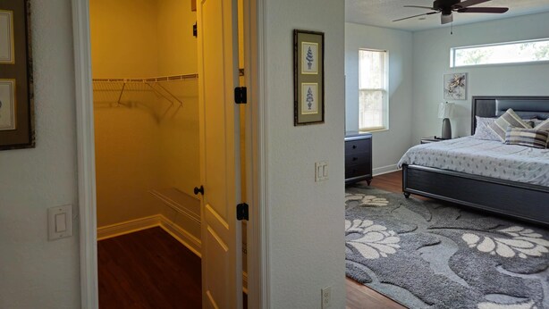 A bedroom with a bed, a ceiling fan, a window, and a door leading to a bathroom. - Countryside Comfort 5 MIN to FAST / WEC & 15 min HITS 1 acre 2 KNG BED Near I-75 (Ocala)