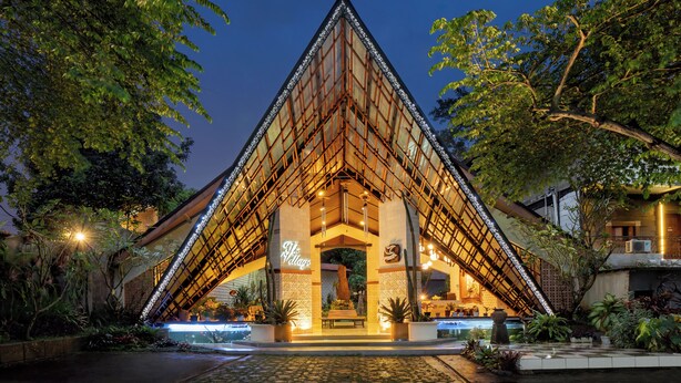 A triangular building with a glass facade and a sign reading "The Village." - The Village Resort Bogor Powered by Archipelago (Caringin)