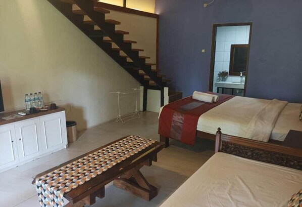 Ein Schlafzimmer mit Bett, einer Bank, einer Treppe und einem Badezimmer im Hintergrund.