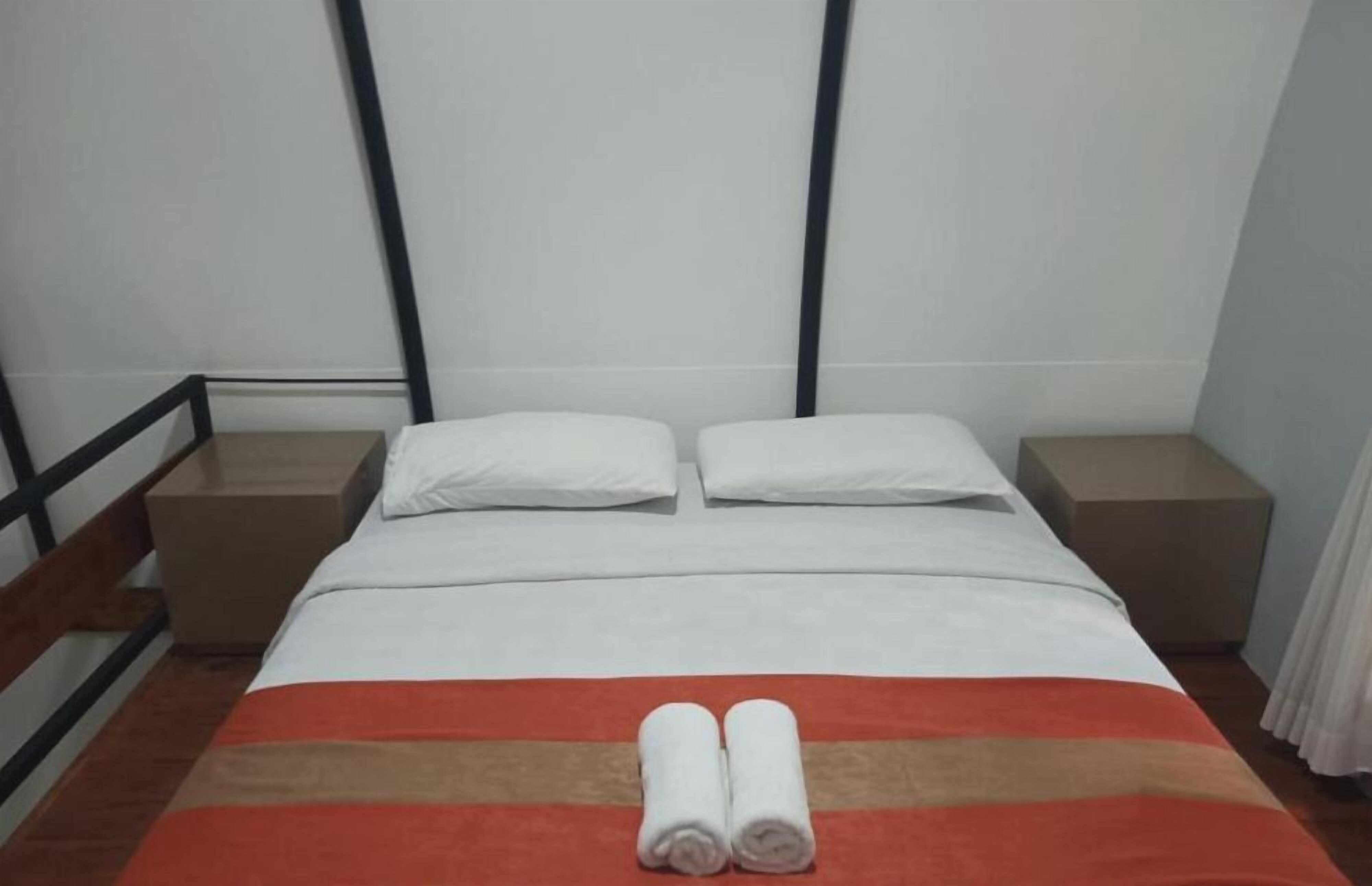 A hotel room with a bed, two nightstands, and a wooden headboard.