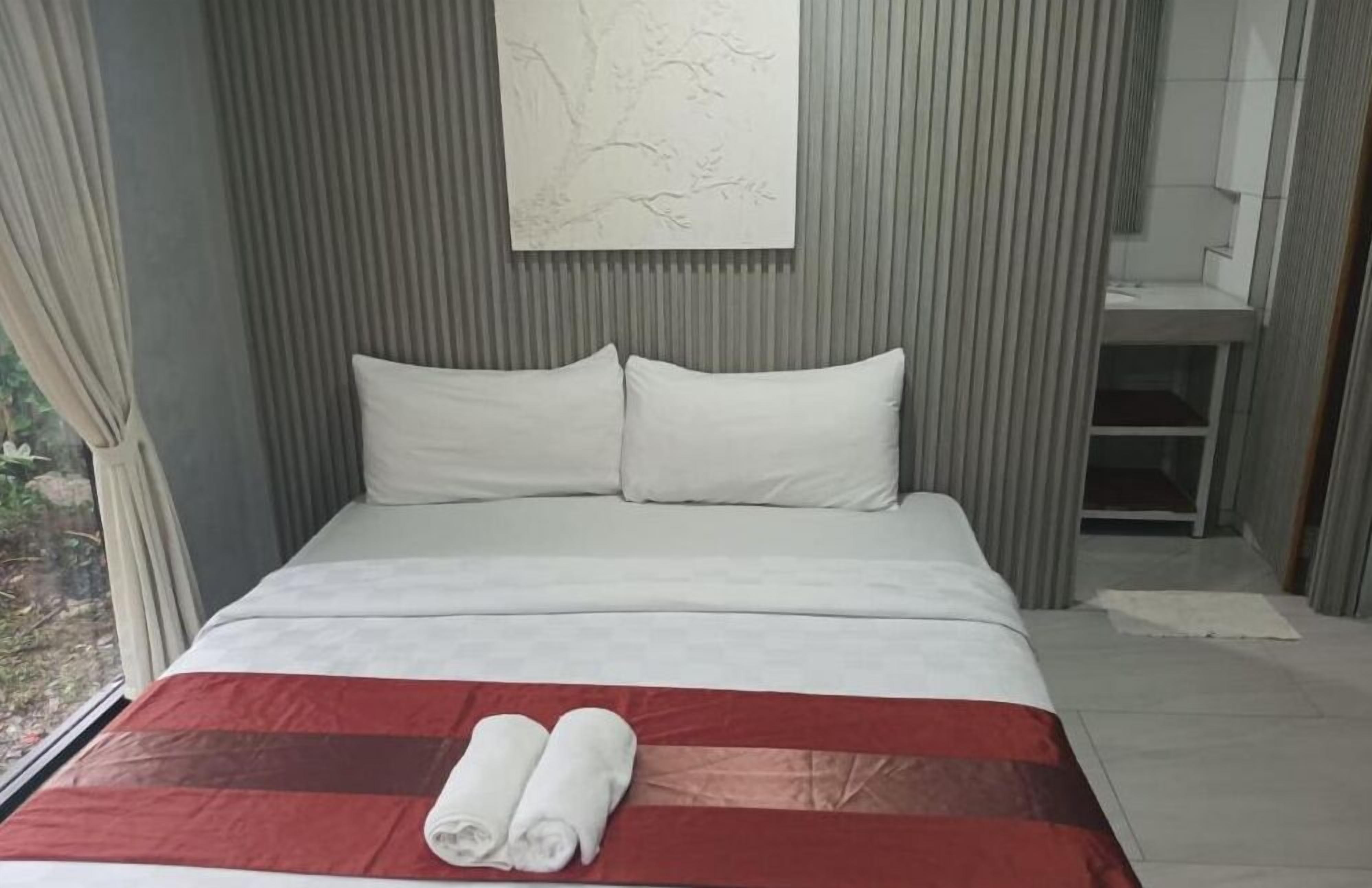 A modern hotel room with a bed, a red and white striped bedspread, and a white pillow.