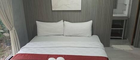 A modern hotel room with a bed, a red and white striped bedspread, and a white pillow.