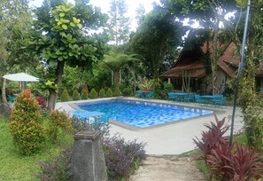 Relax by the serene pool surrounded by lush greenery and tropical plants.