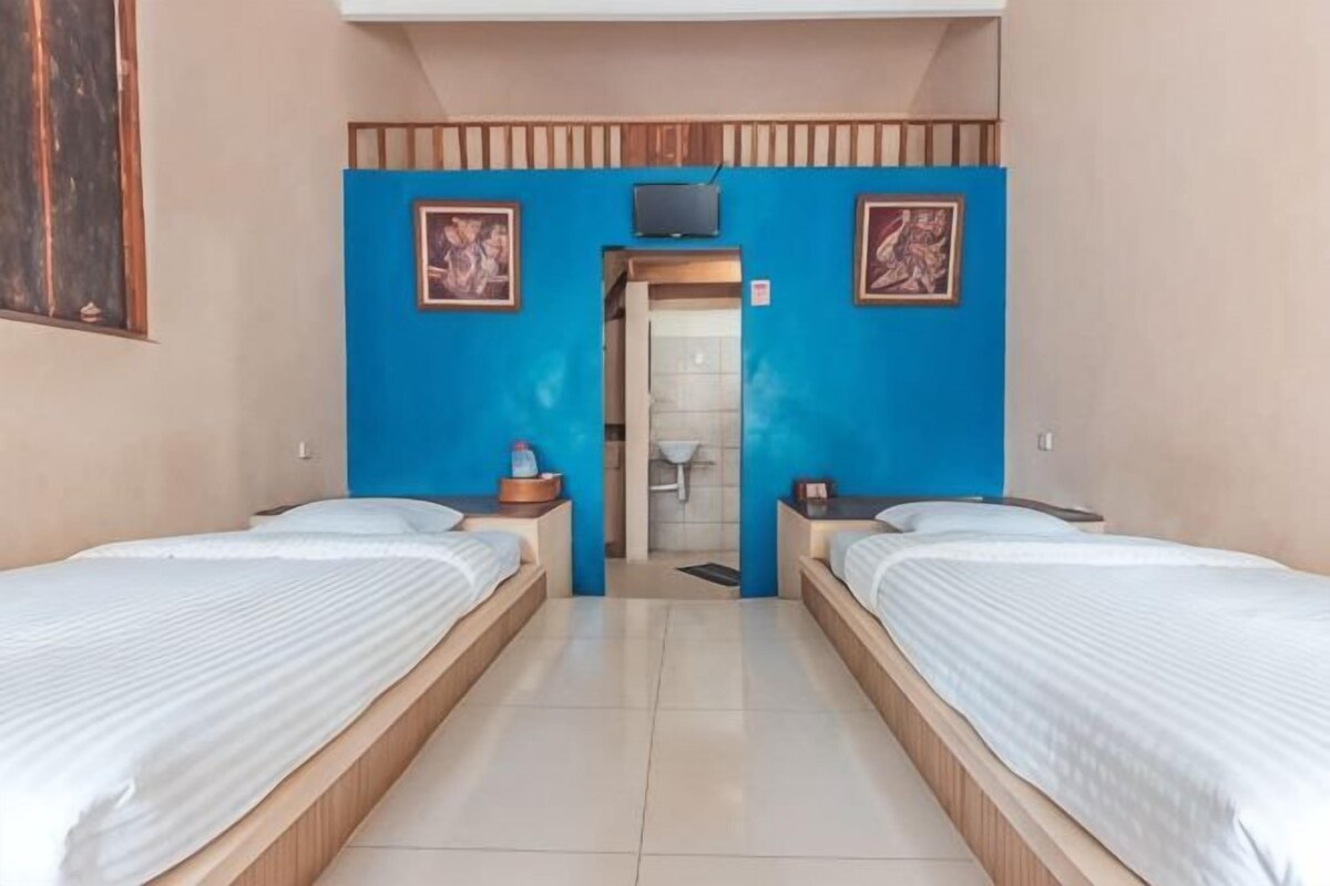 A hotel room with two beds, a television, and a bathroom door.