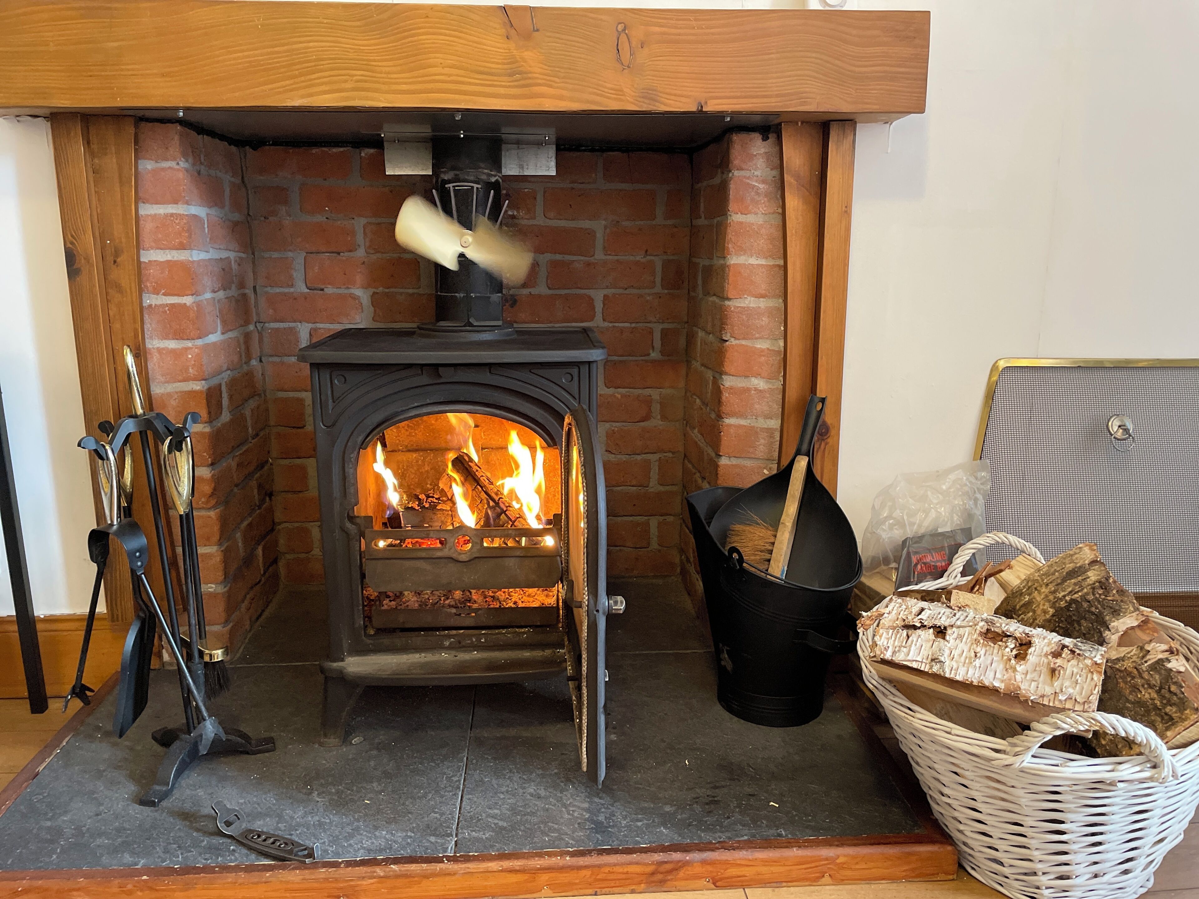 A wood-burning stove with logs and a basket of firewood.