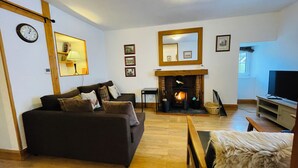 A living room with a fireplace, a sofa, a television, and a mirror.