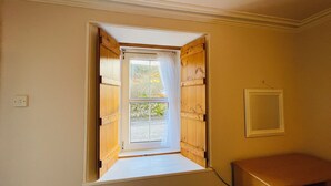 A room with a small window opening to a balcony, wooden walls, and a white ceiling.