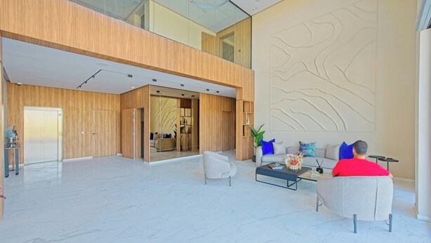 A spacious lobby with a high ceiling, a modern reception desk, and a seating area with sofas and a coffee table.