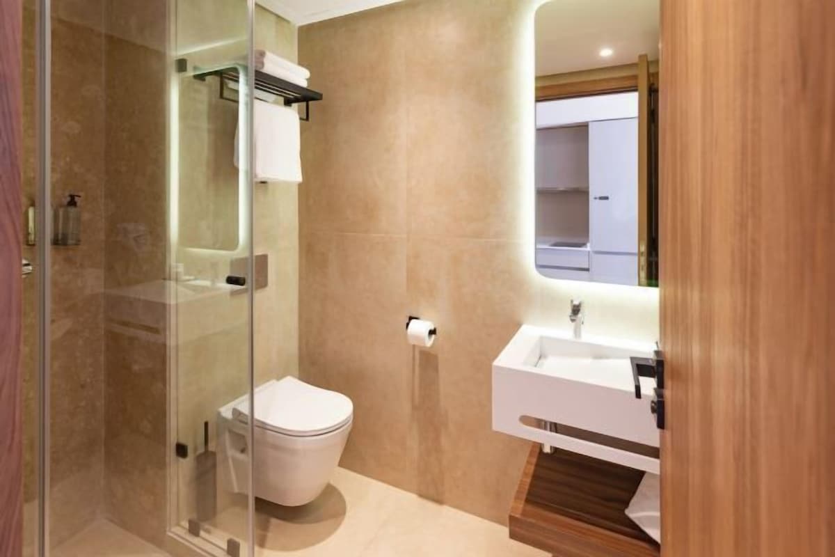Une salle de bain moderne avec une douche à parois de verre, des toilettes blanches et un meuble-lavabo en bois avec un miroir.