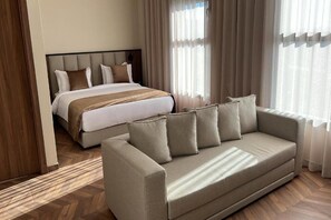 Ein Hotelzimmer mit Bett, Sofa und einem Fenster mit Vorhängen.