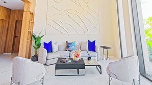 A modern living room with a sofa, two armchairs, a coffee table, and a large window.